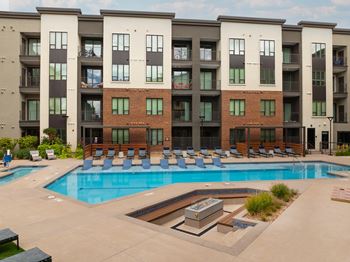 A large swimming pool in front of a multi-story apartment building.